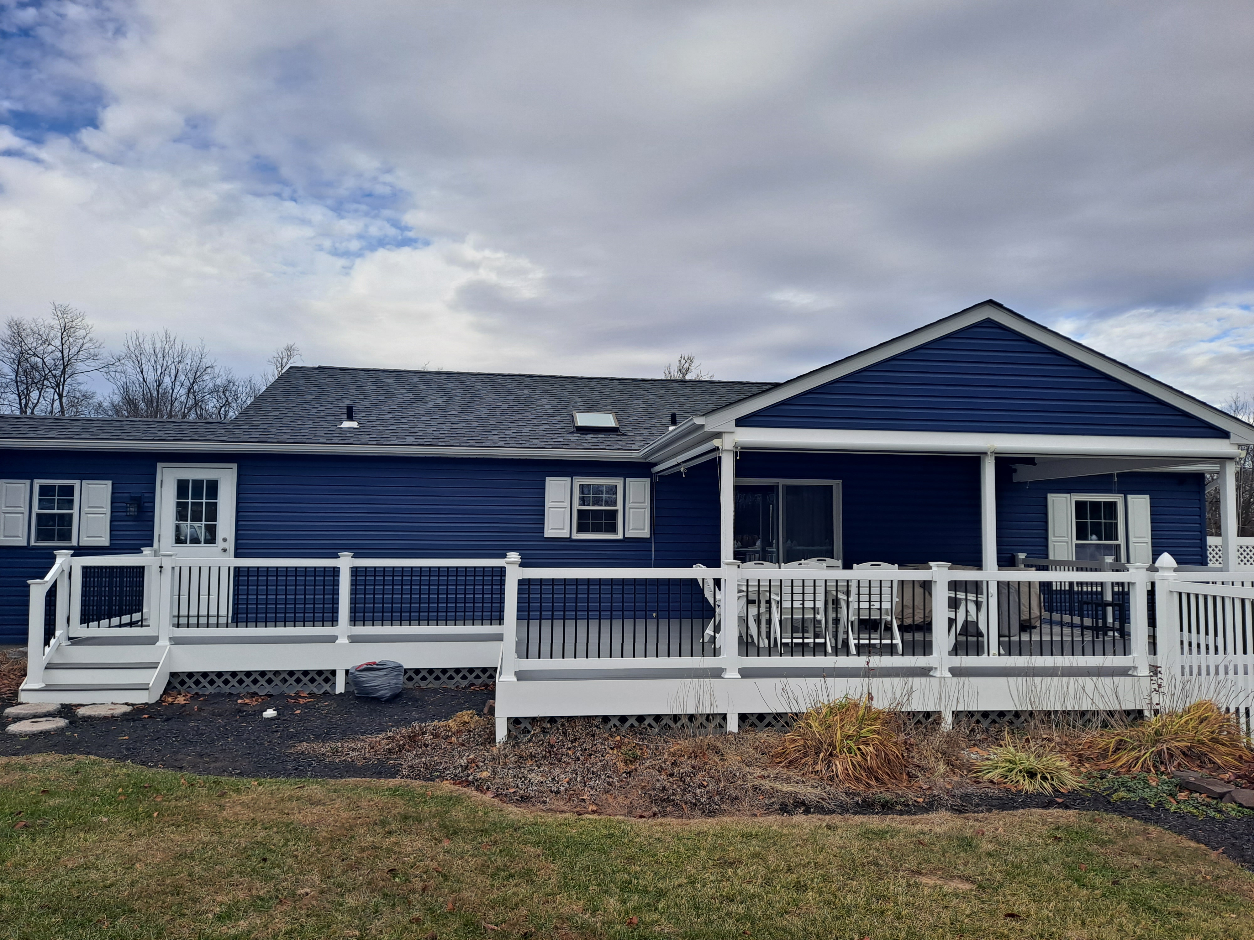 Covered deck addition on a navy blue sided home, full view