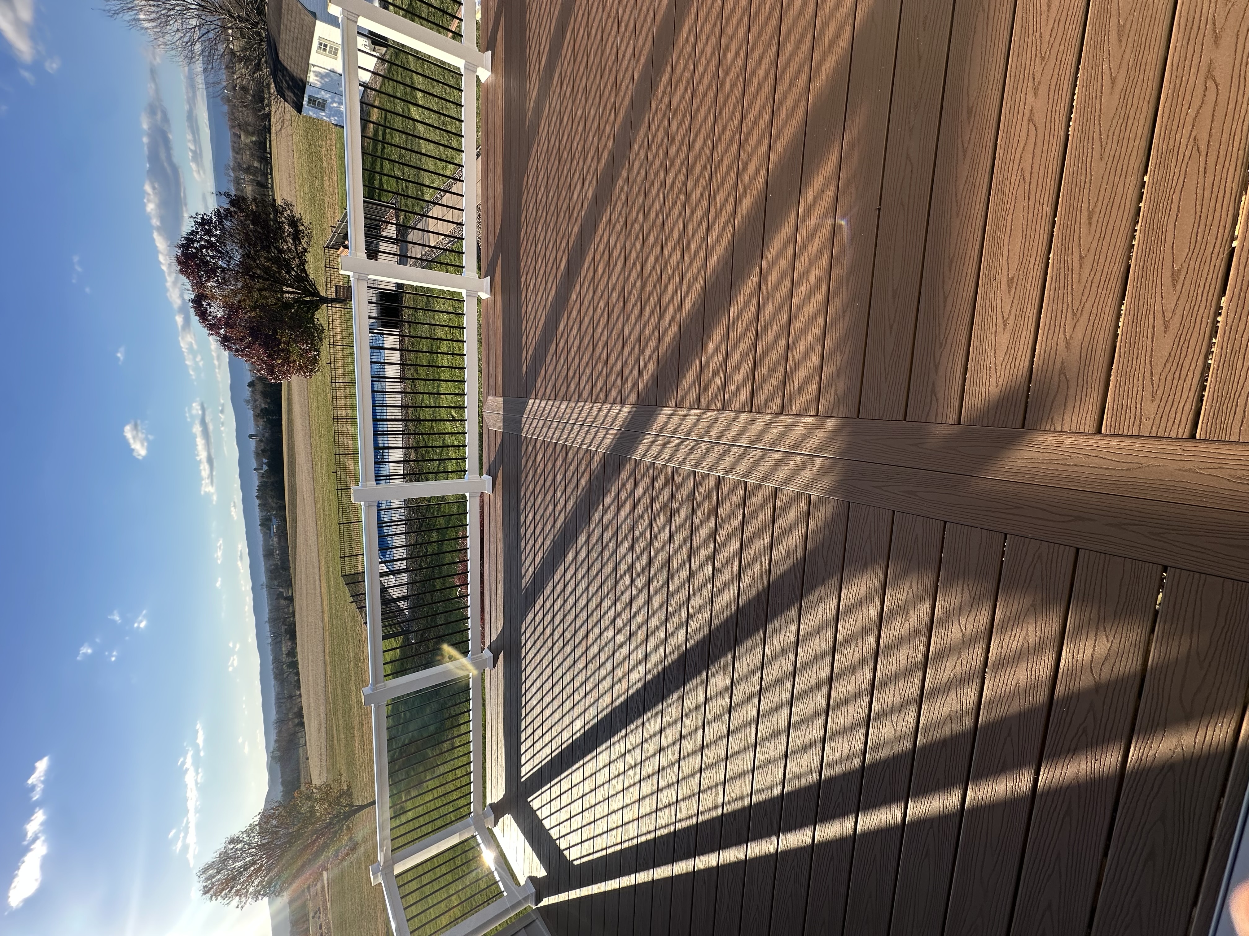 Deck addition overlooking farmland and mountains, with pool below
