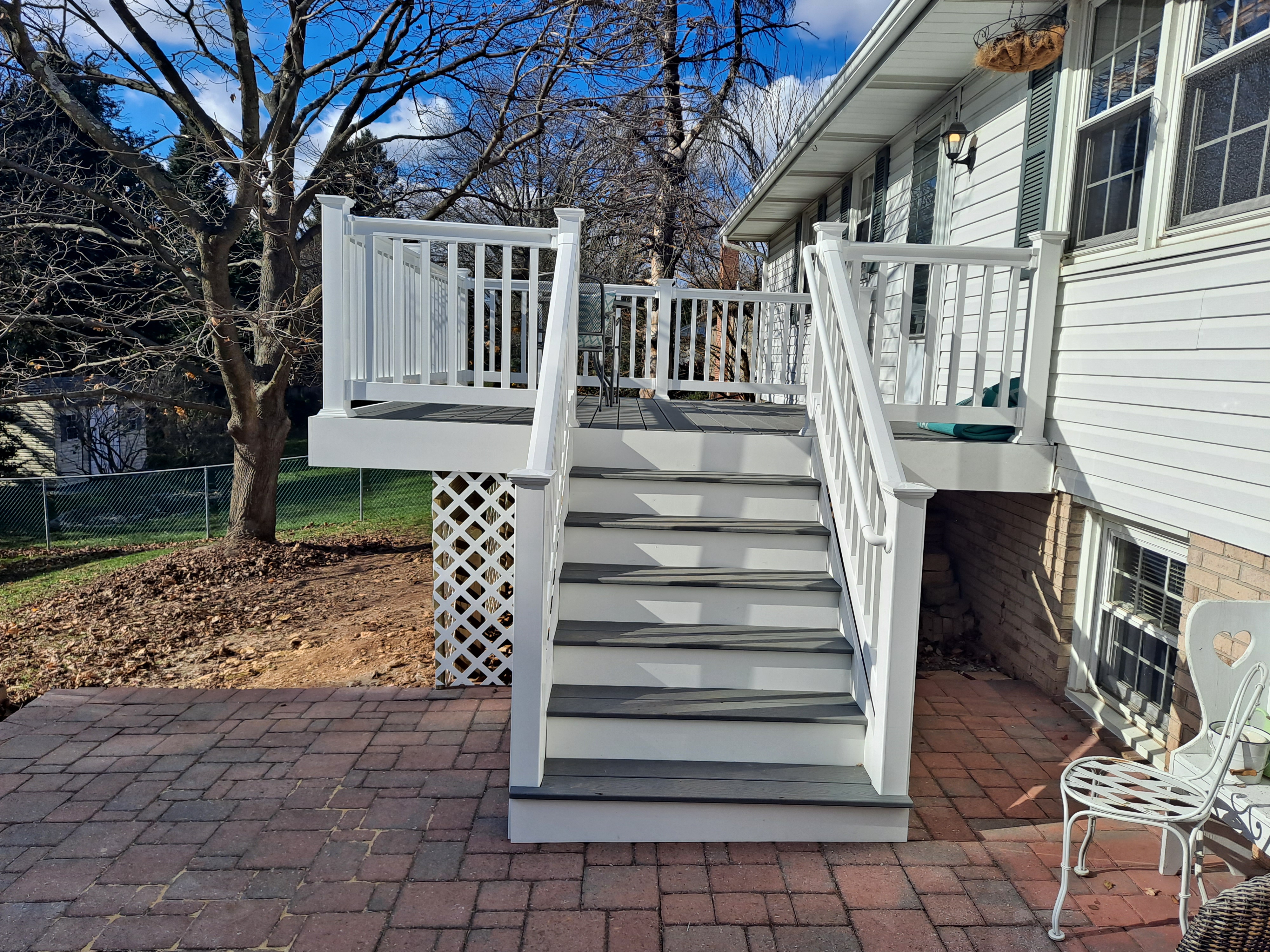 Elevated deck with staircase leading down to a brick patio