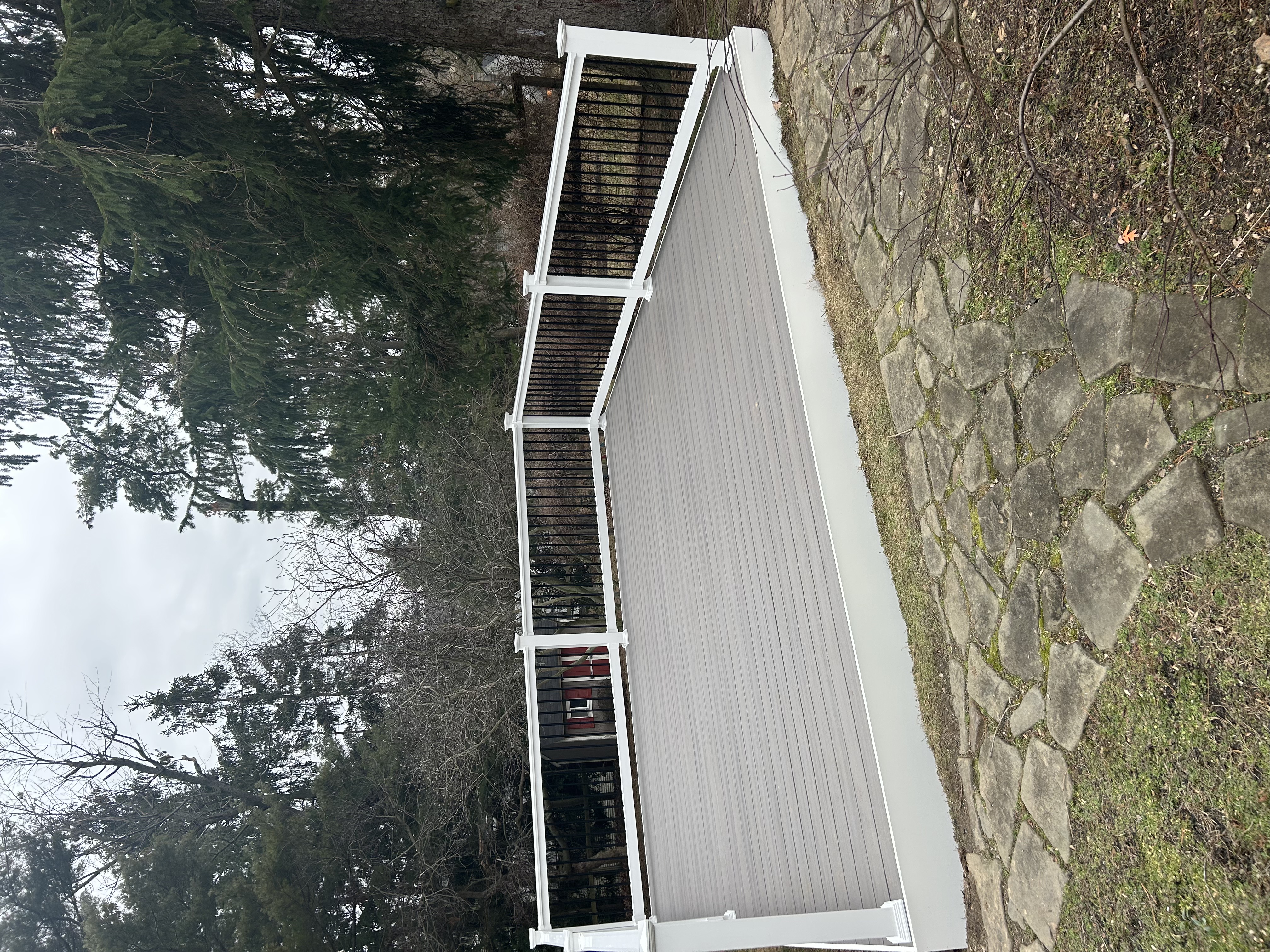Composite deck with white and black railing adjoining a stone patio