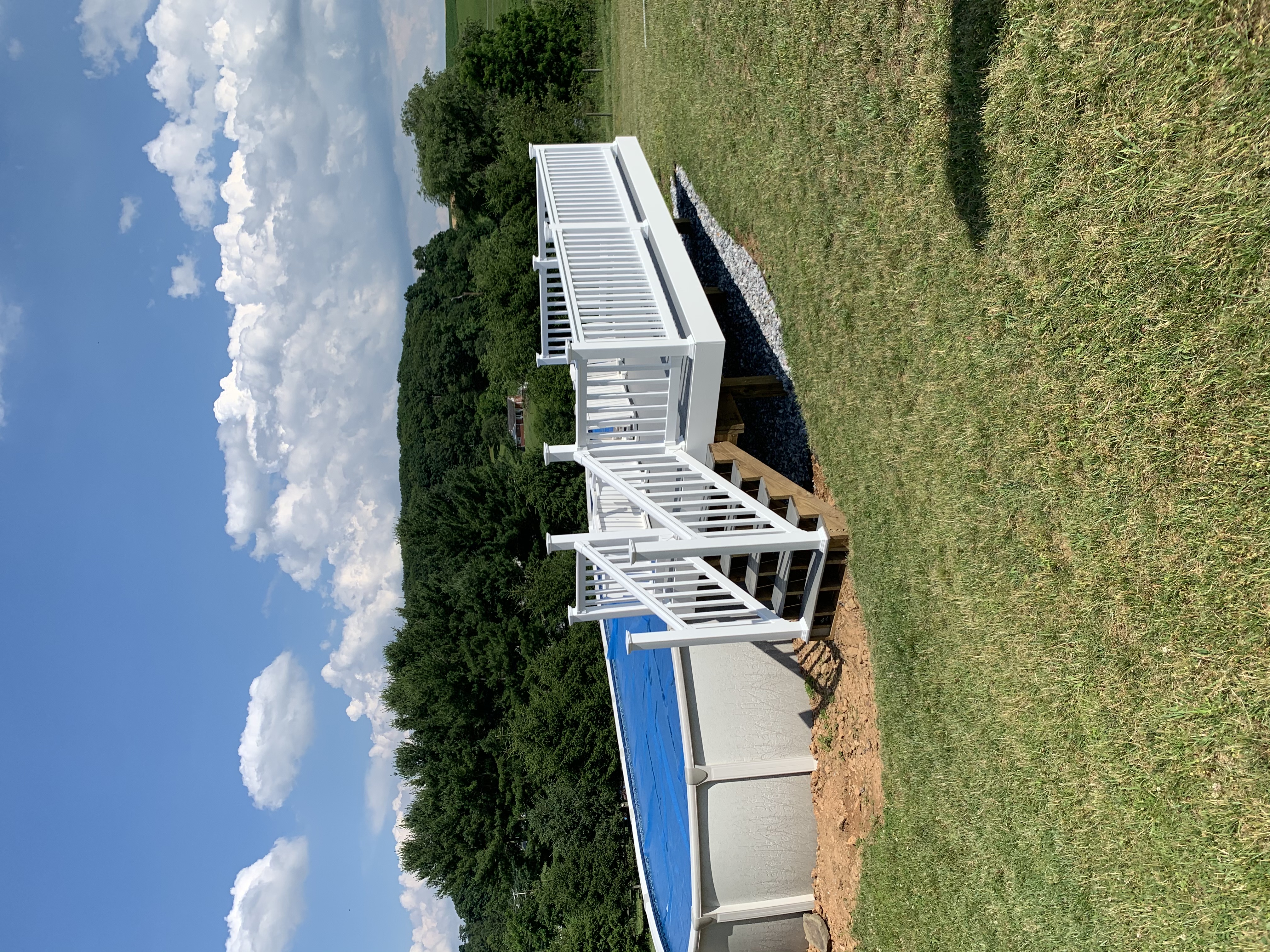 Elevated pool deck with white vinyl railing in a rural setting