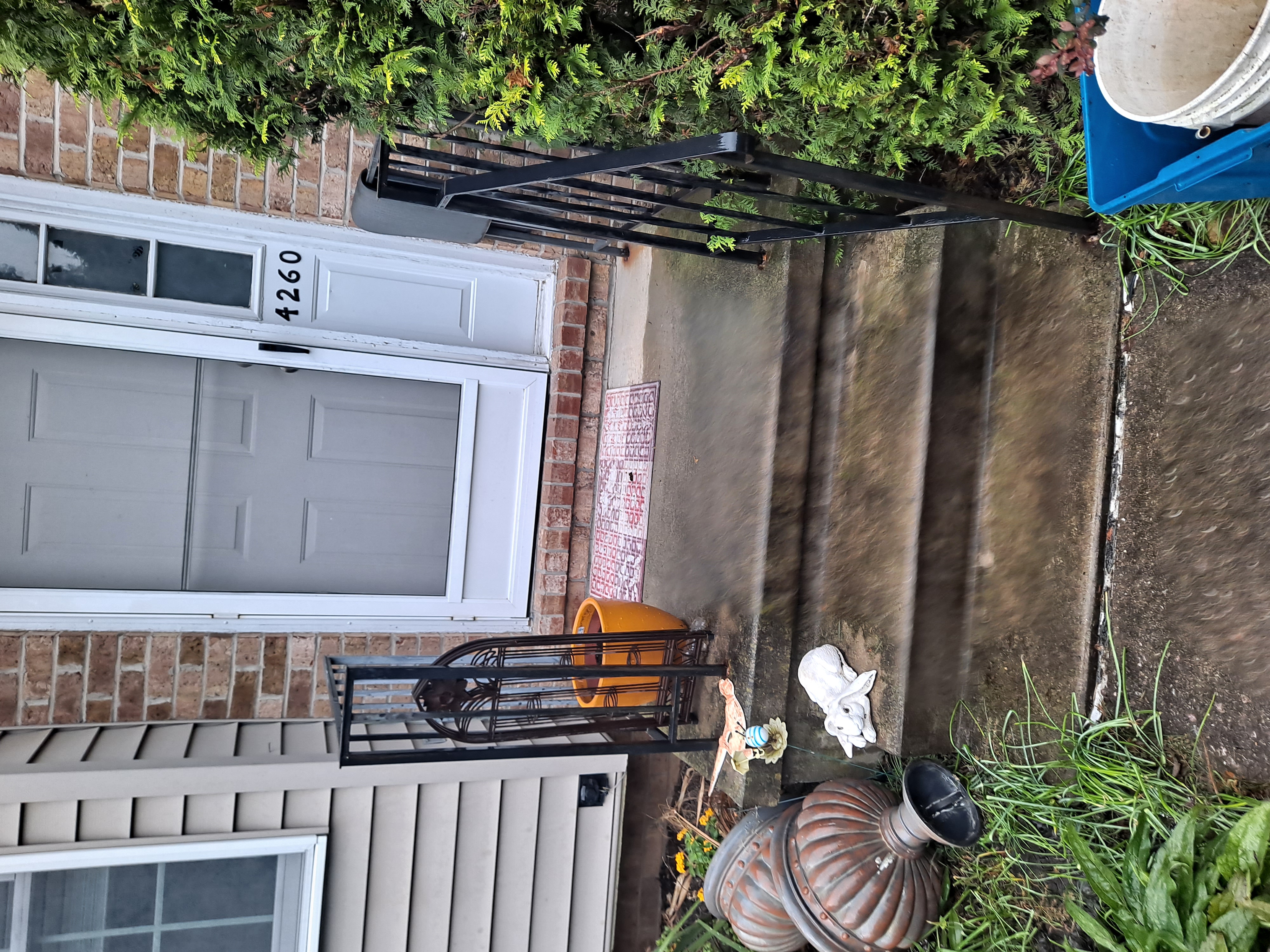 Front entry steps before railing replacement, old black wrought-iron railing
