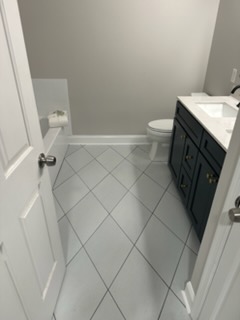 Powder room remodel with diagonal tile floor and navy vanity