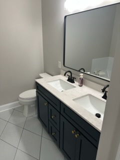 Bathroom remodel with double vanity, toilet, and tile floor